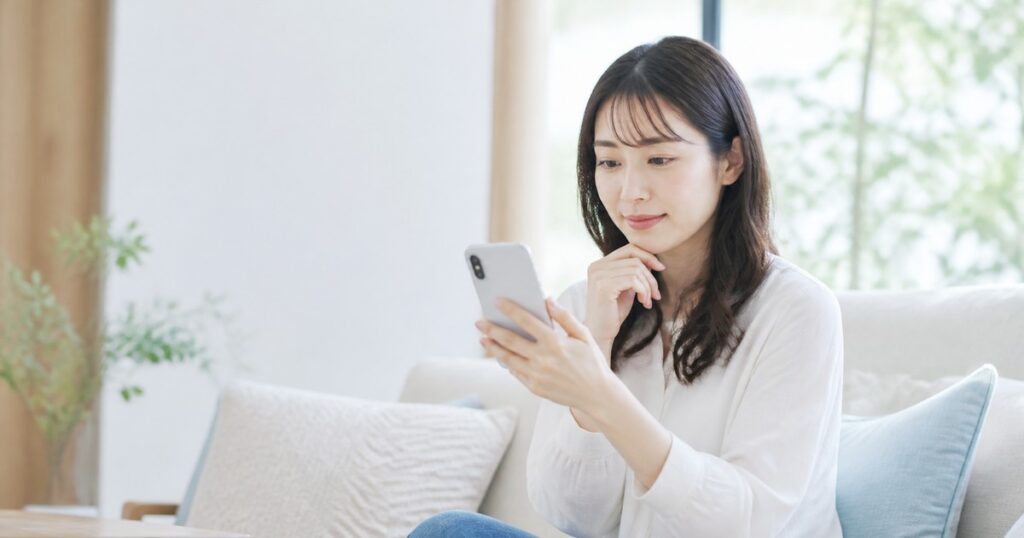 スマートフォンでオンライン診療の予約画面を見る日本人女性