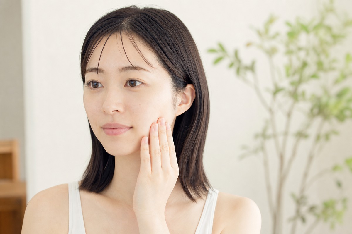 頬に軽く触れて肌の状態を確かめる日本人女性