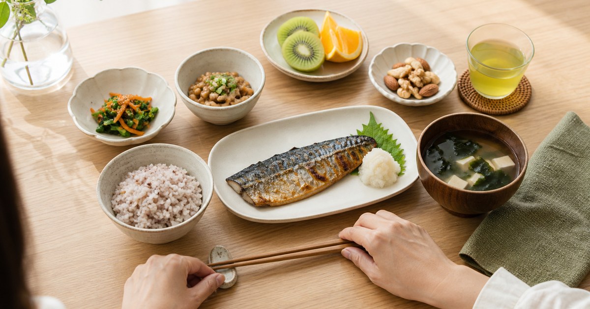 バランスのよい日常的な和食を前に食事を始める日本人女性の手元
